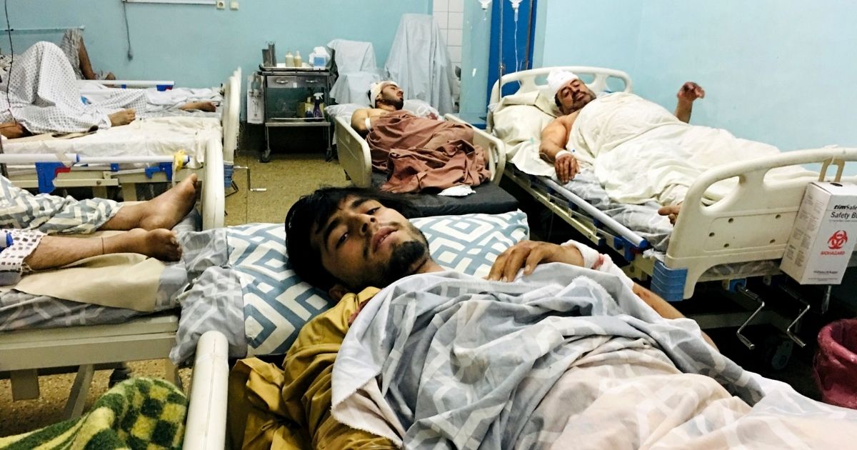 Wounded Afghans lie on a bed at a hospital after a deadly explosions outside the airport in Kabul, Afghanistan, on Thursday.