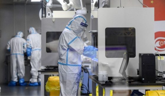 Laboratory technicians wearing personal protective equipment work on samples to be tested for the coronavirus at the Fire Eye laboratory in Wuhan in China's central Hubei province early on Aug. 5, 2021.
