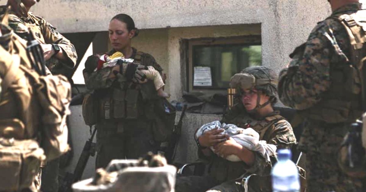 U.S. Marine Sgt. Nicole Gee, left, holds a baby while assisting with the evacuation effort in Kabul, Afghanistan. Gee was killed in a suicide bombing on Thursday.