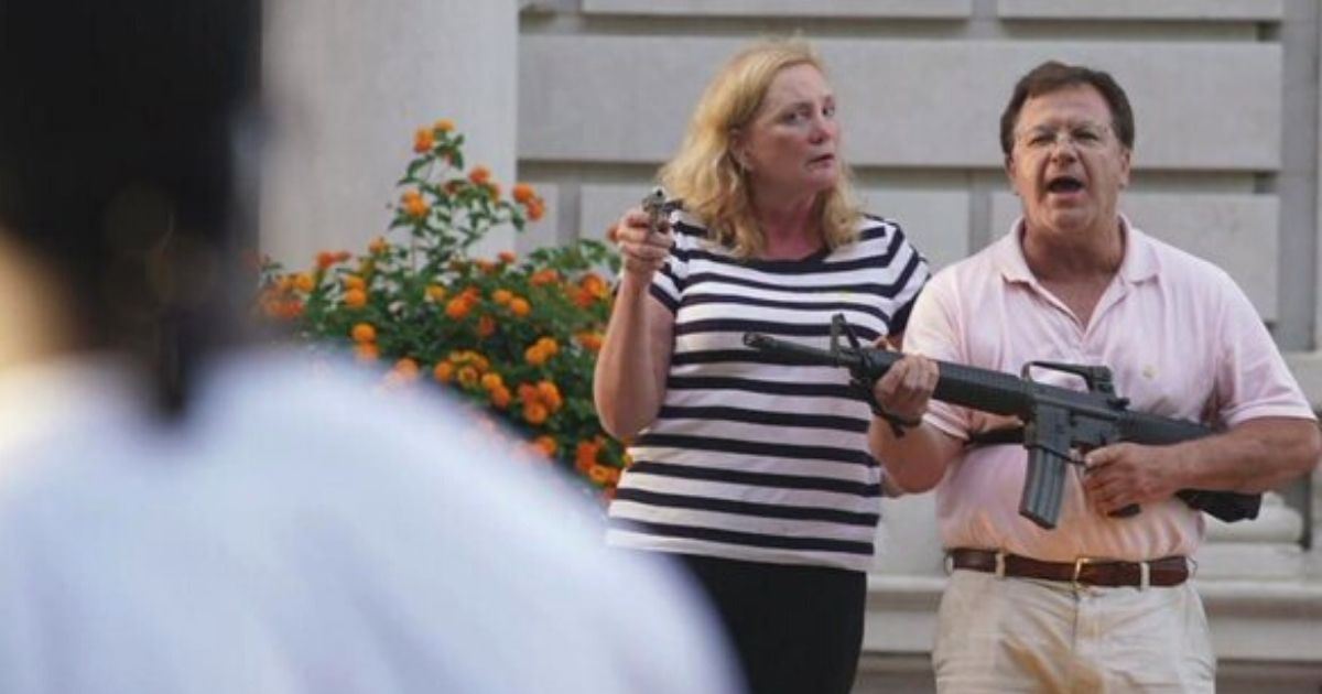 Mark and Patricia McCloskey of St. Louis hold firearms as demonstrators approach their home.