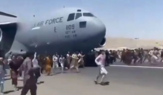 Afghanis crowd the airport runway in Kabul, Afghanistan, trying to stop a plane in hopes of fleeing the country.