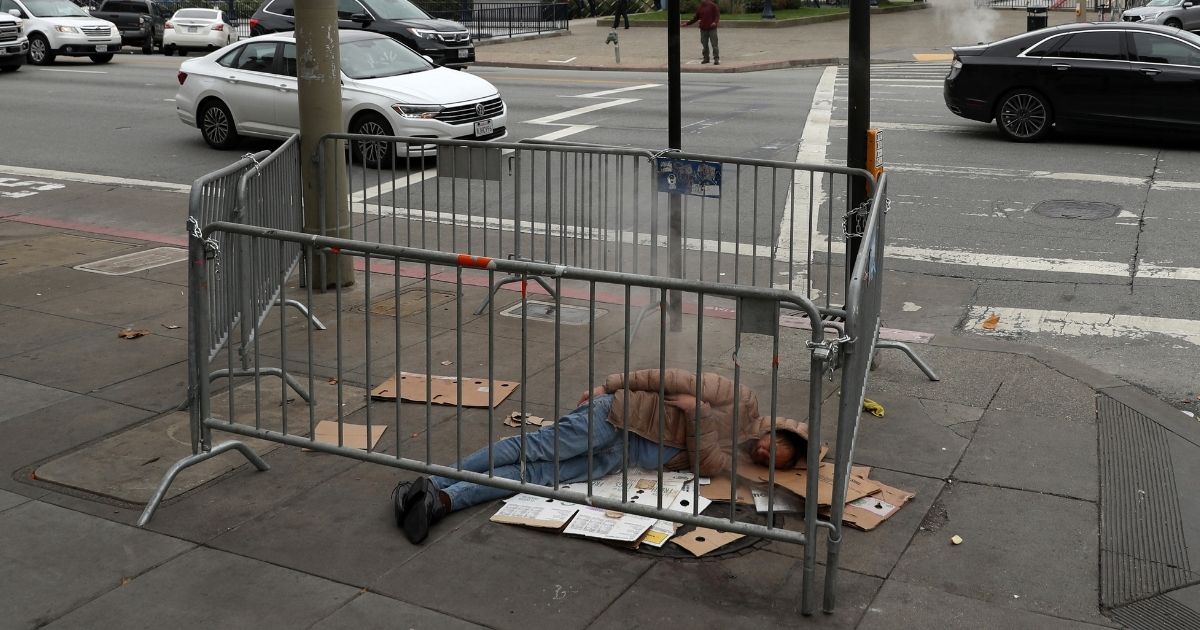 A homeless man sleeps on the sidewalk near San Francisco City Hall on Dec. 5, 2019, in San Francisco.