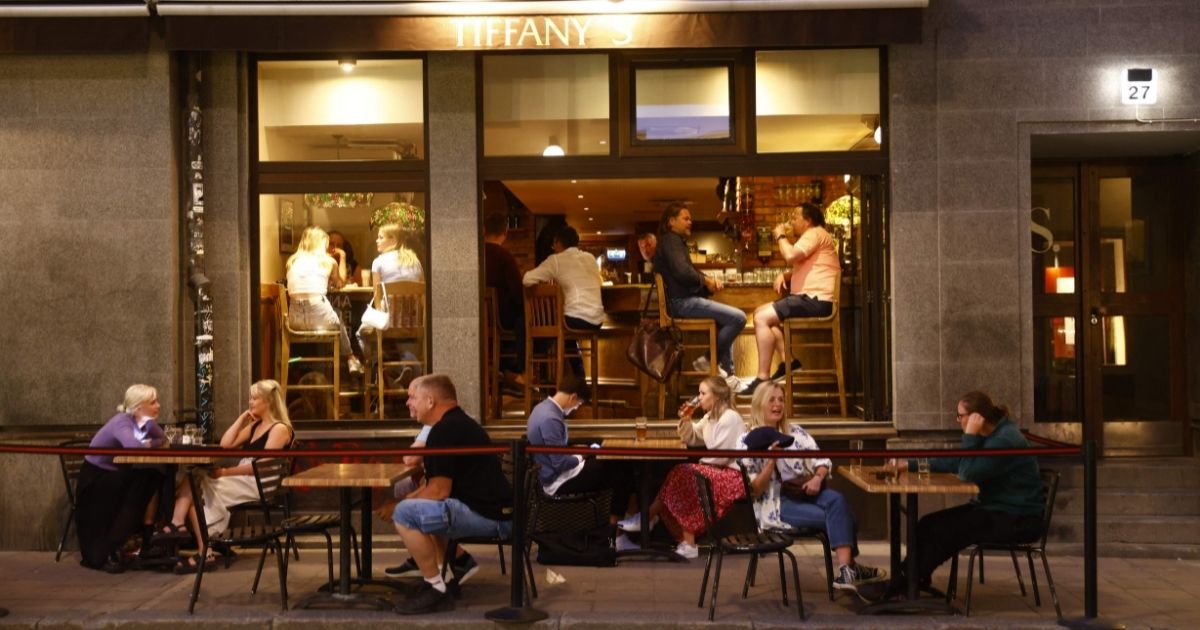 People sit at tables outside a restaurant in Stockholm as COVID restrictions for opening hours at restaurants and bars have been removed completely on July 1, 2021.