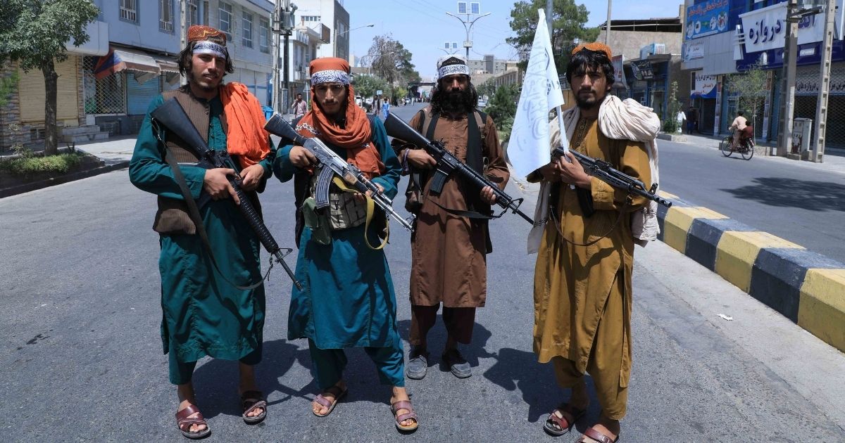 Taliban fighters stand guard along a road in Herat on Thursday amid the Taliban's military takeover of Afghanistan.