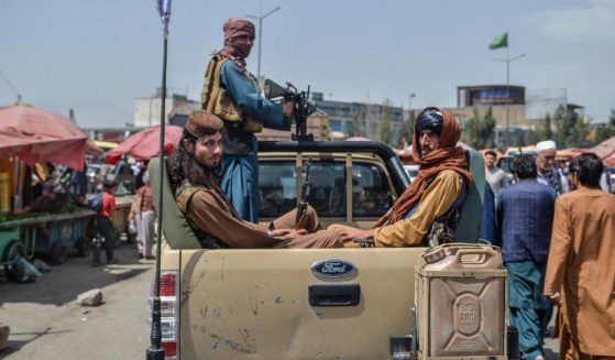 Taliban fighters on a pick-up truck move around a market area, flocked with local Afghan people at the Kote Sangi area of Kabul on Tuesday after Taliban seized control of the capital following the collapse of the Afghan government.