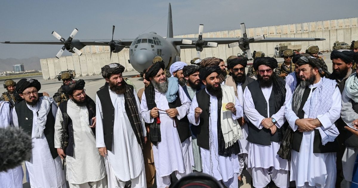 Taliban spokesman Zabihullah Mujahid, center, speaks to the media at the airport in Kabul, Afghanistan, on Tuesday.