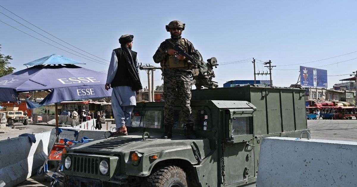 A Taliban fighter stands guard on a Humvee at the main entrance gate of the Kabul airport on Saturday in Afghanistan.