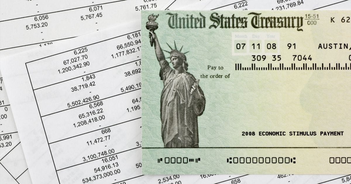 A U.S. Treasury check is pictured atop lists of numbers in the stock image above.