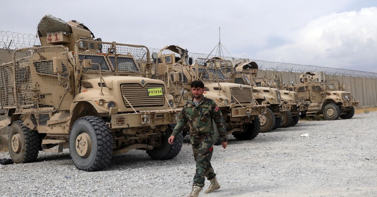 An Afghan army soldier walks past Mine Resistant Ambush Protected vehicles, MRAP, that were left after the American military left Bagram air base, in Parwan province north of Kabul, on July 5, 2021.