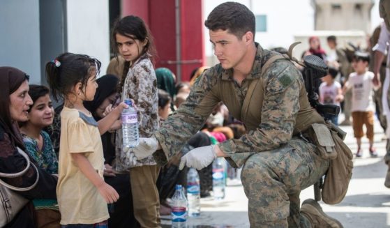 In this image provided by the U.S. Marine Corps, a Marine with the 24th Marine Expeditionary Unit (MEU) provides fresh water to a child during an evacuation at Hamid Karzai International Airport in Kabul, Afghanistan, on Friday.