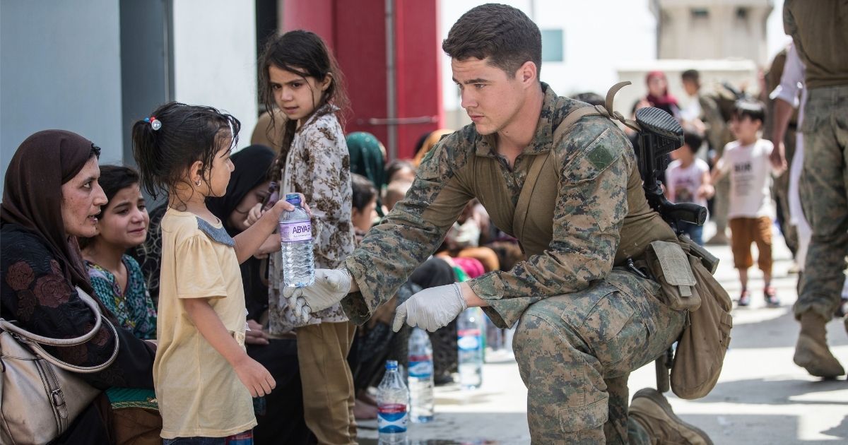 In this image provided by the U.S. Marine Corps, a Marine with the 24th Marine Expeditionary Unit (MEU) provides fresh water to a child during an evacuation at Hamid Karzai International Airport in Kabul, Afghanistan, on Friday.