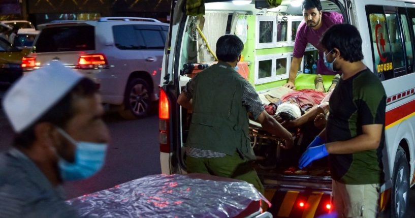 Medical staff bring an injured man to a hospital in an ambulance after two powerful explosions, which killed at least six people, outside the airport in Kabul on Thursday.