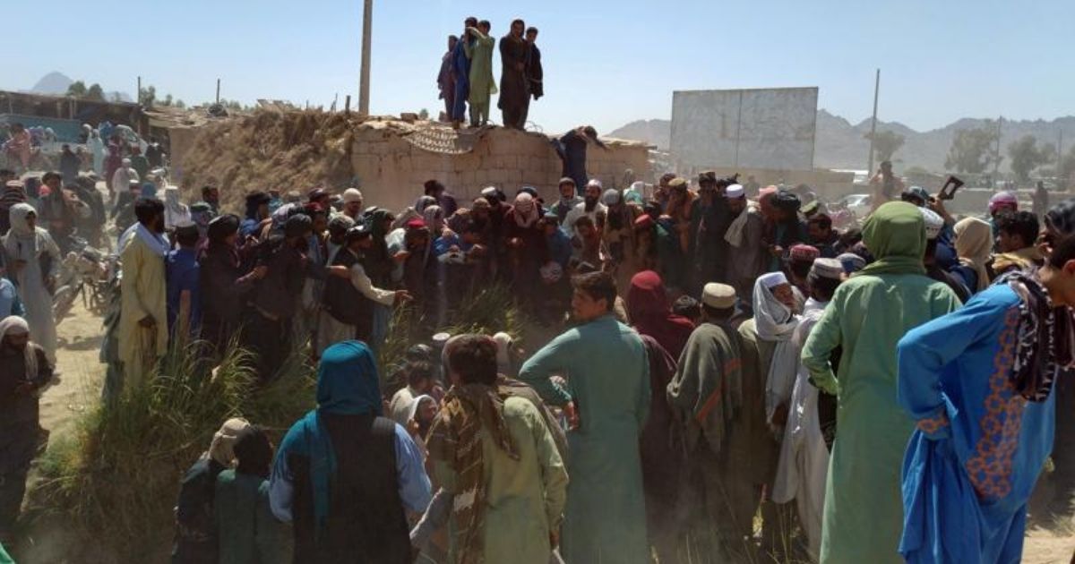 Taliban fighters and Afghans are seen gathered around a body in the city of Farah in southwest Afghanistan on Wednesday.