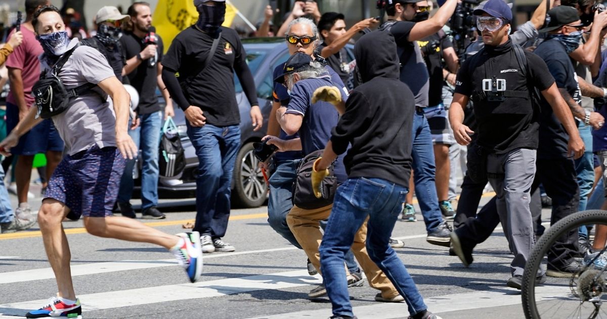 Anti-vaccination demonstrators, left, clash with counter-protesters during an anti-vaccination protest in front of City Hall in Los Angeles on Aug. 14, 2021.