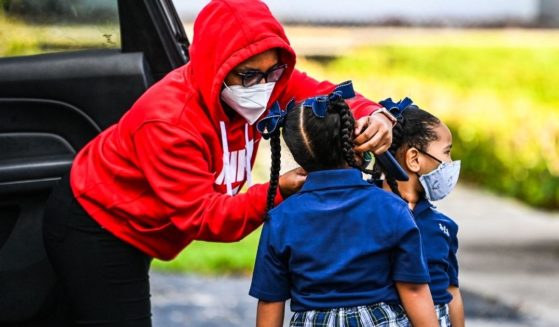 A mother adjusts the mask of her child as she prepares to enter her Miami-area school on Aug. 18, 2021, on the first day of classes after summer vacation.
