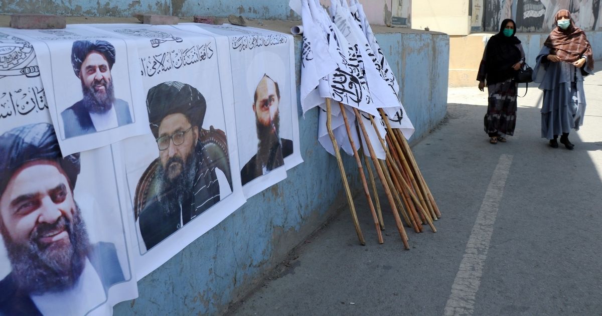 Afghan women walk by posters of Taliban leaders and flags in Kabul, Afghanistan, last week.