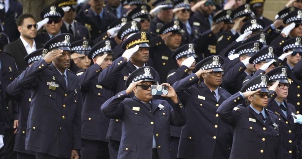 A group of Chicago police officers salute as fellow officer Ella French’s body is carried into the St. Rita of Cascia Shrine Chapel on Thursday.