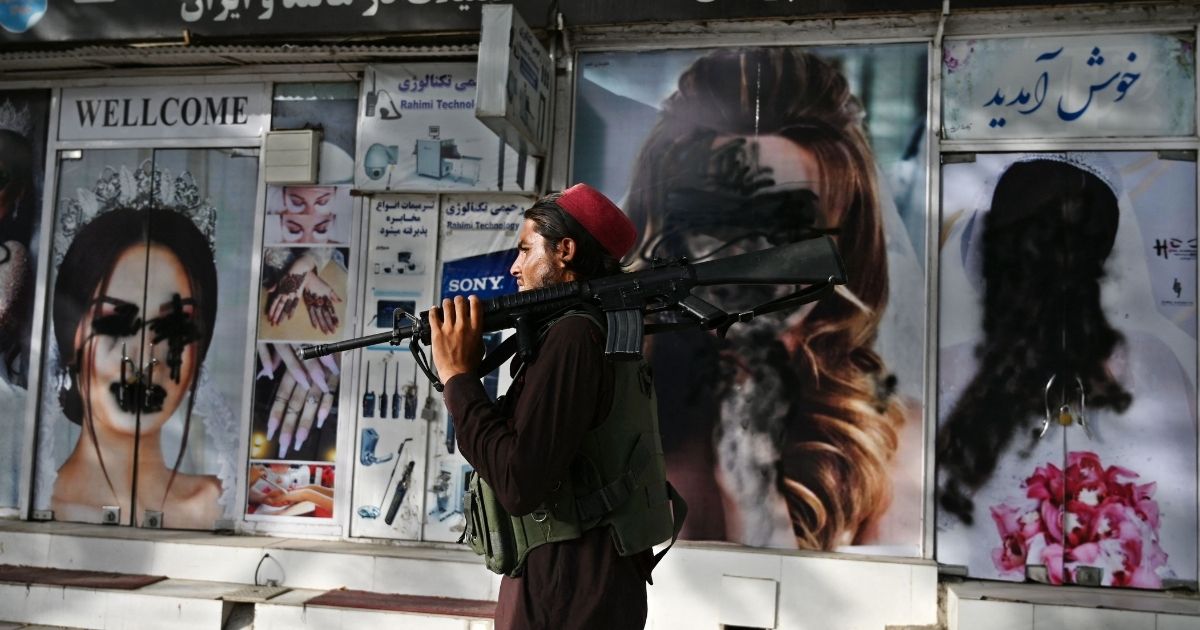 A Taliban fighter walks past defaced images of women in Kabul, Afghanistan, on Wednesday.