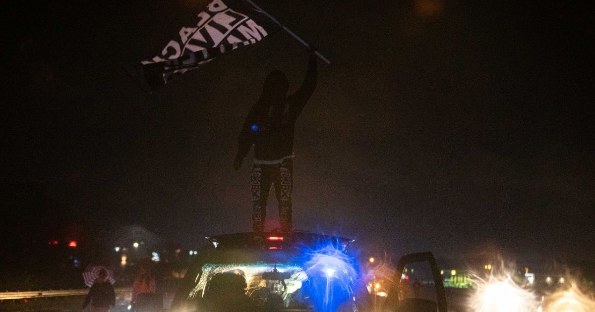 A rioter stands on a car and waves a Black Lives Matter flag in Elizabeth City, North Carolina, on April 24, 2021.