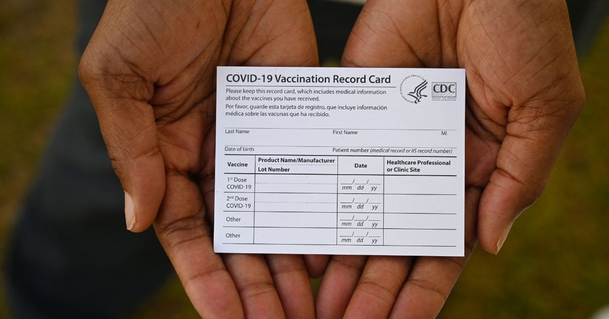A health care worker holds a COVID-19 vaccination record card at a QueensCare Health Center in Los Angeles on Aug. 11, 2021.