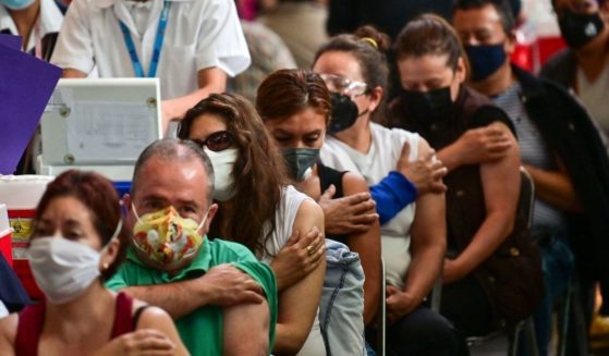 A group of people wait in a vaccination center after receiving Pfizer's COVID-19 vaccine.