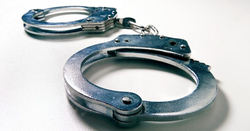 A stock photo depicts a pair of handcuffs.