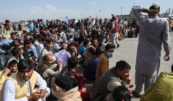 Afghan passengers sit as they wait to leave the airport in Kabul on Monday after a stunningly swift end to Afghanistan's 20-year war, as thousands of people mobbed the city's airport trying to flee the group's feared hardline brand of Islamist rule.