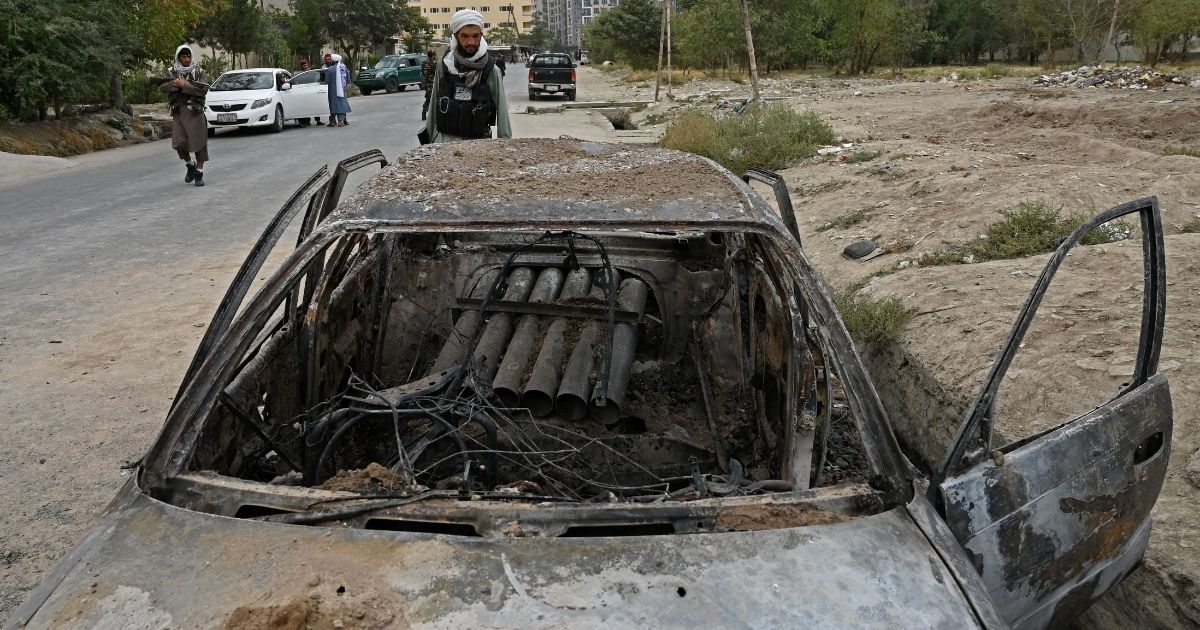 A Taliban fighter investigates a damaged car Monday after multiple rockets were fired in Kabul.