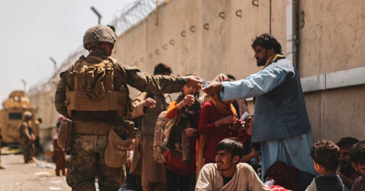 This handout image shows A Marine with the 24th Marine Expeditionary unit (MEU) passes out water to evacuees during an evacuation at Hamid Karzai International Airport, Kabul, Afghanistan, Aug. 22.