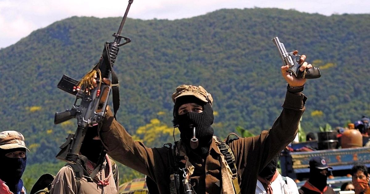 Masked Zapatista Subcommander Marcos smokes a pipe and displays weapons Feb. 24, 2001, in La Realidad, Mexico.