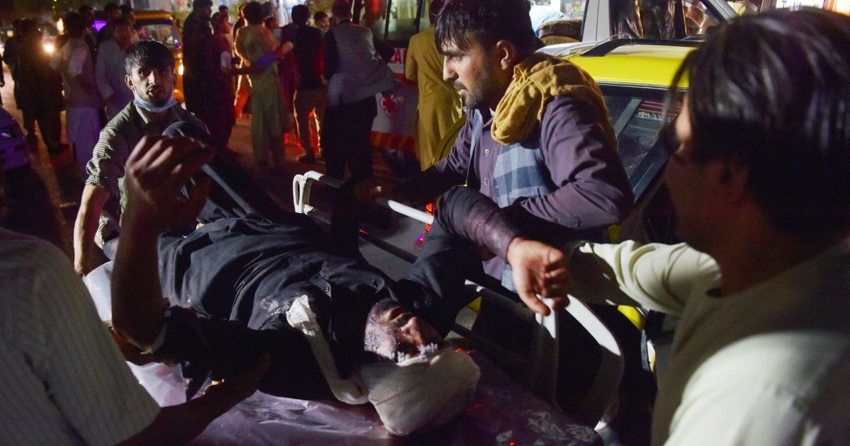 Medical and hospital staff bring an injured man on a stretcher for treatment after two blasts, which killed at least five and wounded a dozen, outside the airport in Kabul on Thursday.