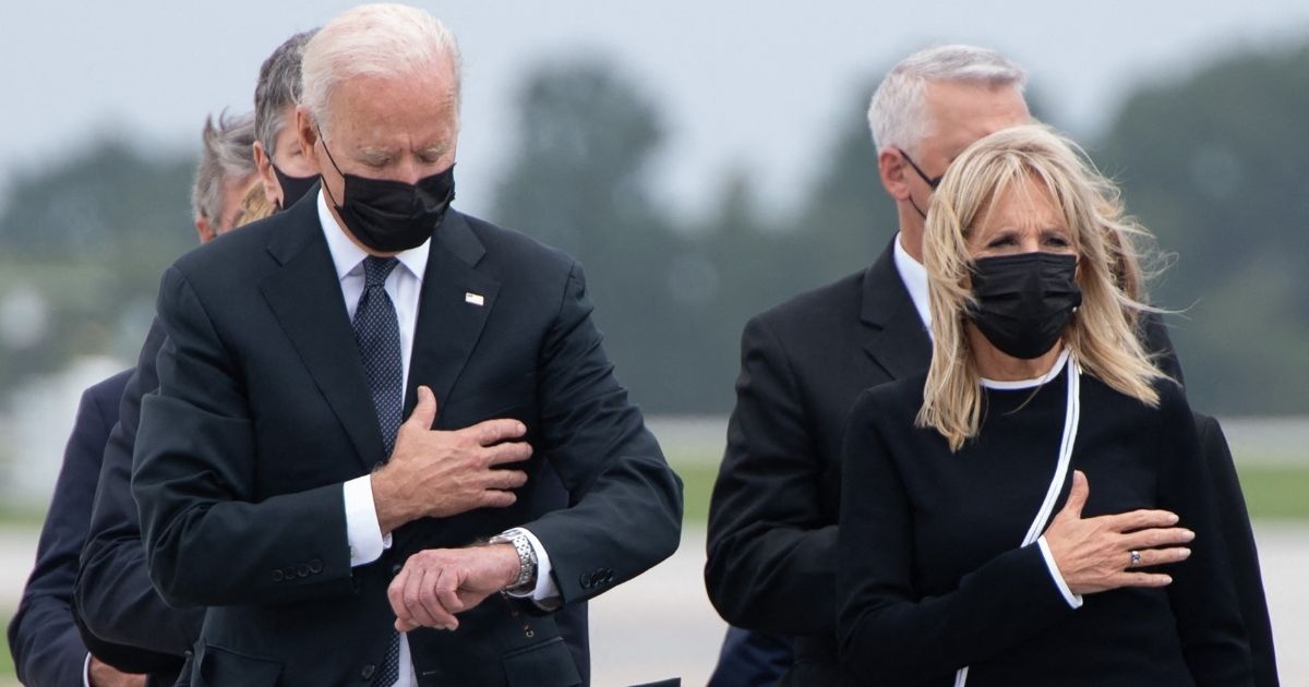 President Joe Biden is seen looking at his watch while attending the dignified transfer of the remains of fallen service members at Dover Air Force Base in Dover, Delaware, on Sunday.