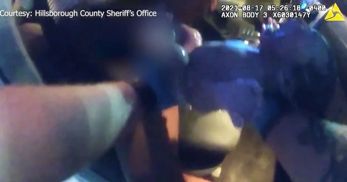 A Florida sheriff's deputy holds a newborn baby after assisting a laboring mother in a car on Tuesday.