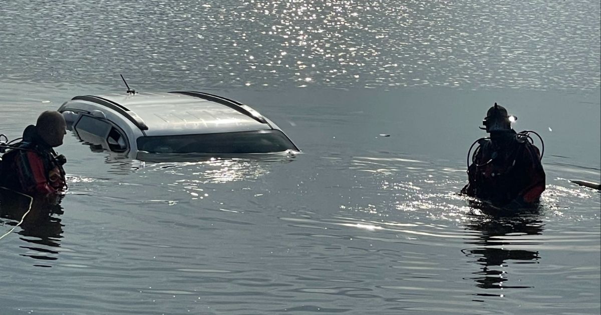 Divers are pictured in the water near a submerged car in the Cooper River.