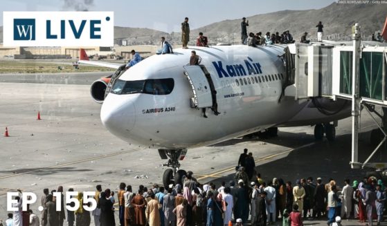 Afghan people climb atop a plane as they wait at the Kabul airport in Kabul on Monday.