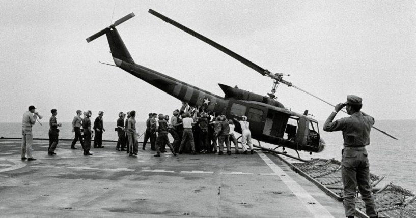 U.S. Navy personnel aboard the USS Blue Ridge push a helicopter into the sea off the coast of Vietnam in order to make room for more evacuation flights from Saigon, on April 29, 1975. The helicopter had carried Vietnamese fleeing Saigon as North Vietnamese forces closed in on the capital.