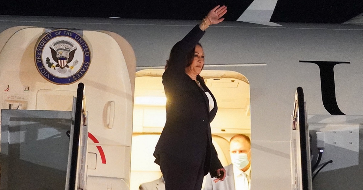 Vice President Kamala Harris waves from the door of Air Force Two.