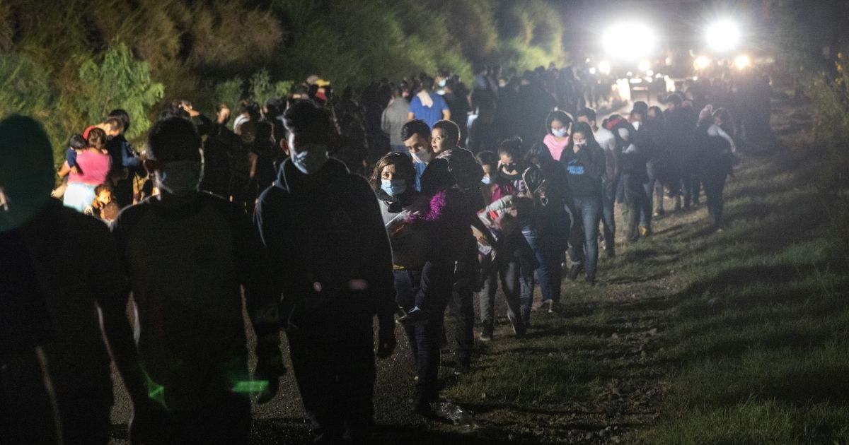 Illegal immigrants walk toward transport buses to a processing center on Aug. 14, 2021, in Roma, Texas.
