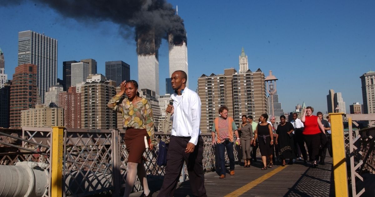 People walk over the Brooklyn Bridge as the World Trade Center burns on Sept. 11, 2001, in New York City.