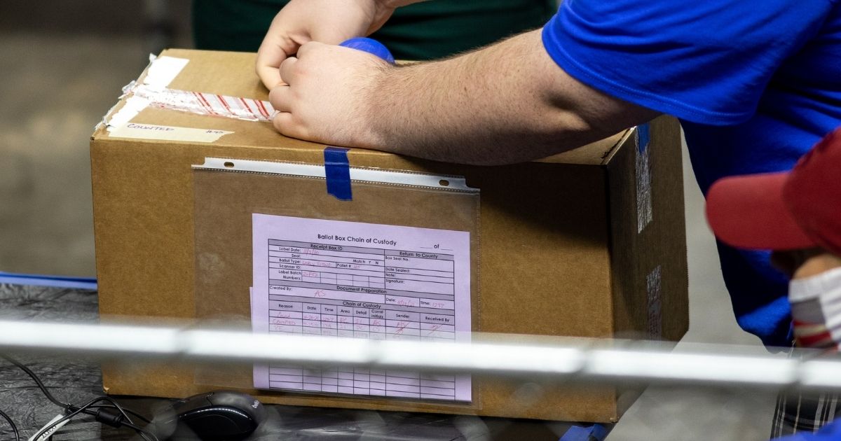 A contractor working for Cyber Ninjas, who was hired by the Arizona State Senate, unboxes ballots from the 2020 general election at Veterans Memorial Coliseum on May 1, 2021, in Phoenix.