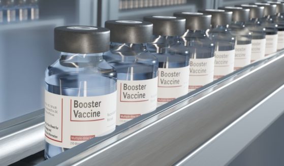 This stock image portrays a line of booster shots of the COVID-19 vaccine on a conveyor belt. An article in The Lancet medical journal quotes departing FDA officials who raise questions about the Biden administration's vaccine booster program.