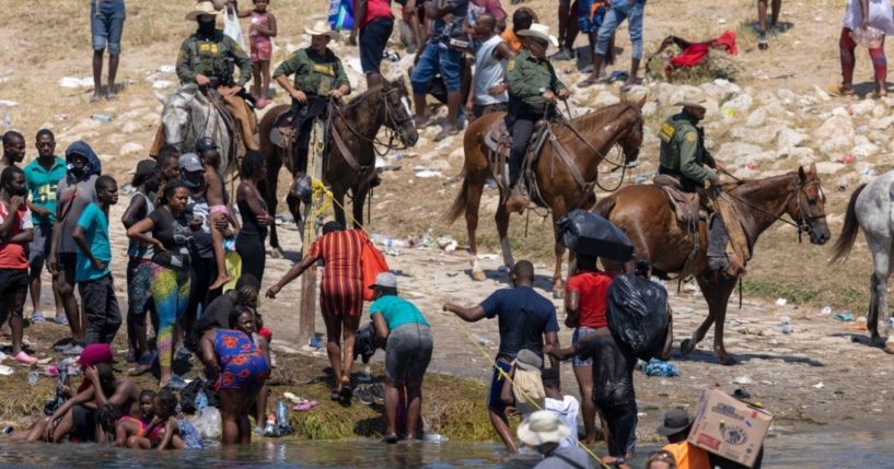 Mounted U.S. Border Patrol agents watch Haitian immigrants on the bank of the Rio Grande in Del Rio, Texas on Monday.