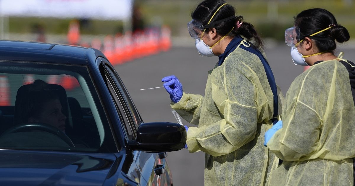 Medical personnel prepare to administer a COVID-19 text at a drive through testing center in California.