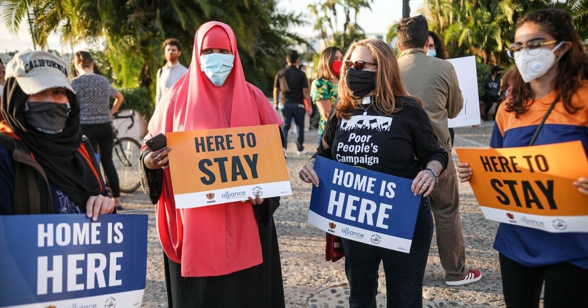 People hold signs during a rally in support of the Obama administration's Deferred Action for Childhood Arrivals program in San Diego on June 18, 2020.