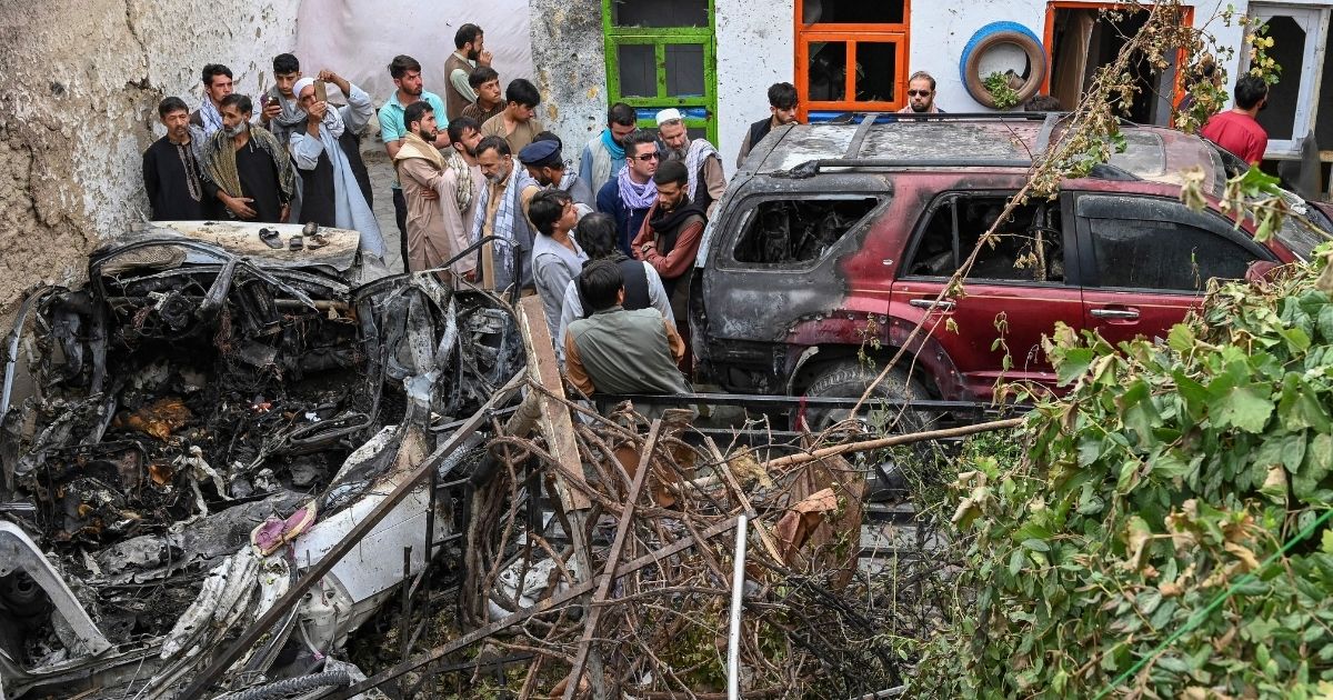 Afghan residents and family members of the reported victims gather next to a damaged vehicle outside a house, after a U.S. drone airstrike in Kabul allegedly killed 10 people on Aug. 30, 2021.