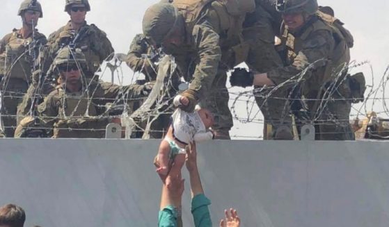 A U.S. Marine grabs an infant over a fence of barbed wire during an evacuation at Hamid Karzai International Airport in Kabul, Afghanistan, on August 19, 2021.