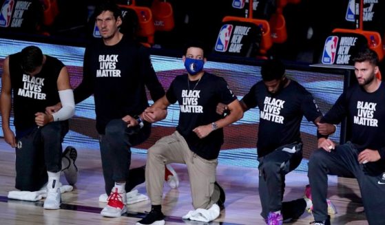 Members of the NBA's Dallas Mavericks kneel during the playing of the national anthem prior to a game against the Los Angeles Clippers at the ESPN Wide World of Sports Complex in Lake Buena Vista, Florida, on Aug. 6, 2020.