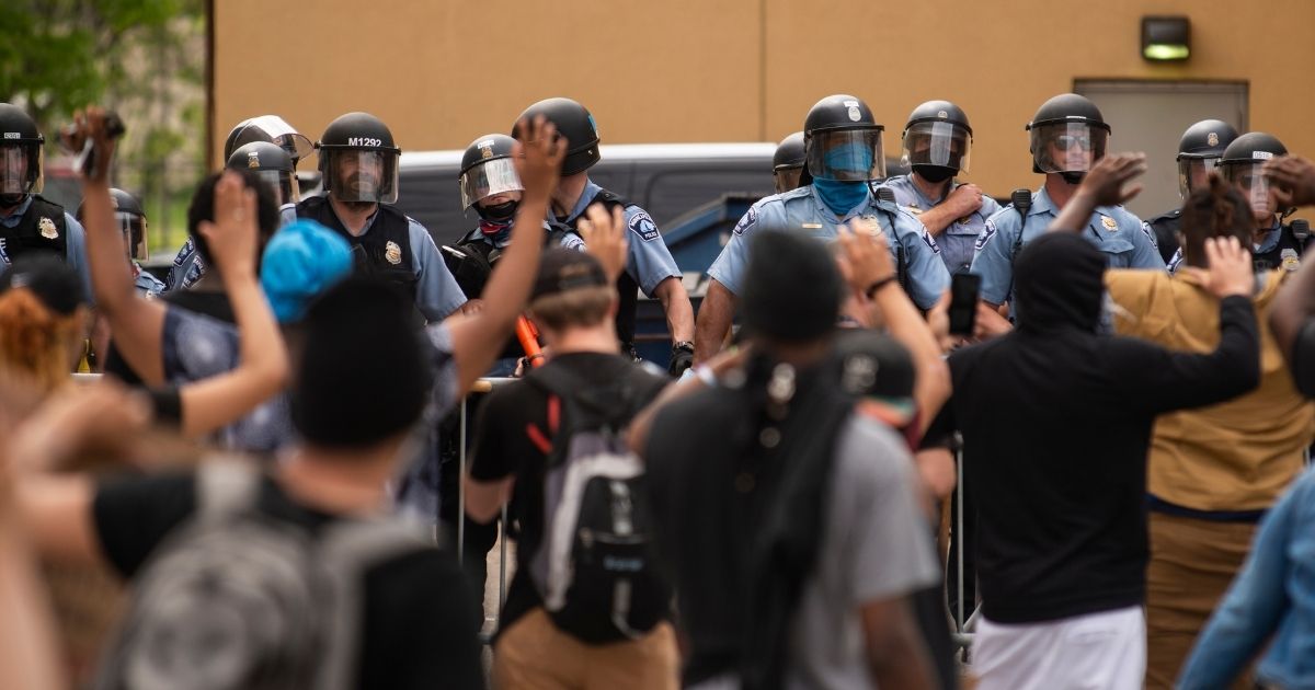 Police officers stand in a line while facing demonstrators outside the 3rd Police Precinct in Minneapolis on May 27, 2020.