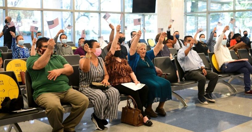 New U.S. citizens wave flags at the conclusion of a naturalization ceremony ahead of World Refugee Day by U.S. Citizenship and Immigration Services on June 17, 2021, in Los Angeles.
