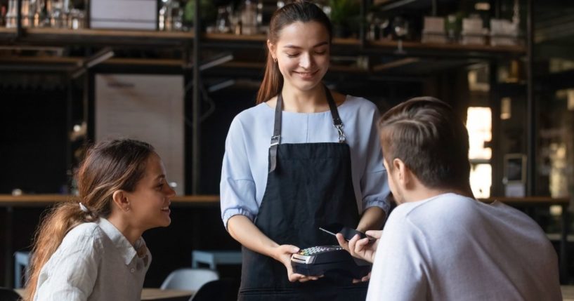 A restaurant server is pictured with a couple at a table in the stock image above.